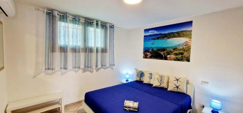 a bedroom with a blue bed and a painting on the wall at La casa al mare, Pittulongu in Olbia