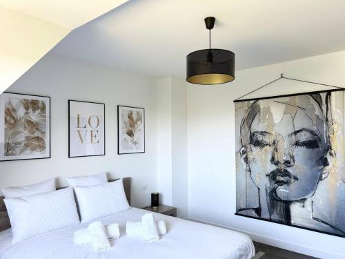 - une chambre avec un lit blanc et une peinture murale dans l'établissement Belle maison rénovée à la plage, à Fouesnant