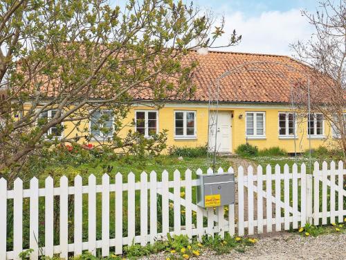 een wit hek voor een geel huis bij 11 person holiday home in r sk bing in Ærøskøbing