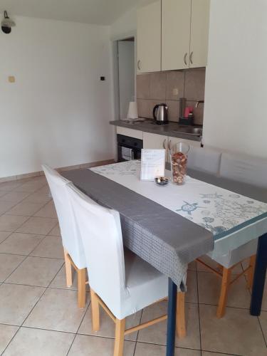 een keuken met een tafel en 2 witte stoelen bij Lana 1 in Senj