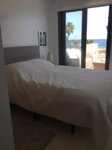 um quarto com uma cama e vista para o oceano em Beachfront penthouse with sunroof em Arenales del Sol