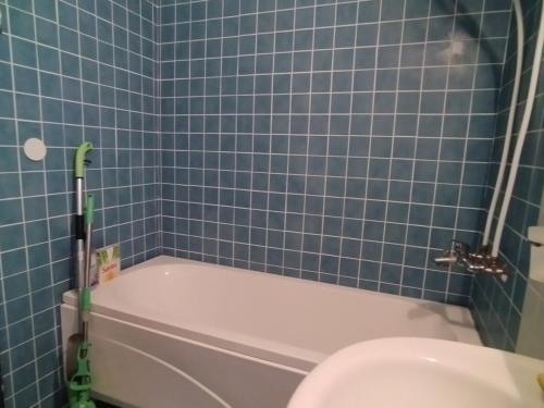 a blue tiled bathroom with a tub and a toilet at Апартамент Тита in Burgas