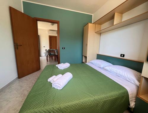 1 dormitorio con 1 cama verde y 2 toallas en Case Vacanza Calabria Ionica, en Cropani