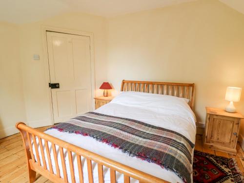 a bedroom with a wooden bed with a blanket on it at Myrtle Villa in Knighton
