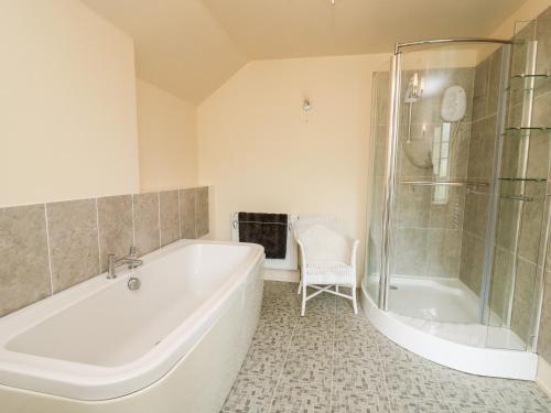 a white bathroom with a tub and a shower at Myrtle Villa in Knighton