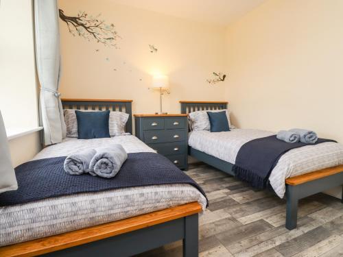 a bedroom with two beds with towels on them at Lonnon Cottage in Alnwick