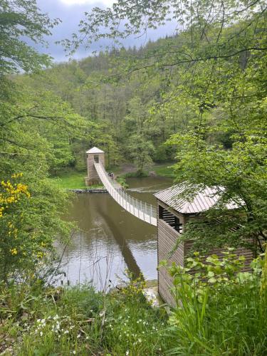 a suspension bridge over a river in a forest at B&B ArdennesT in Bouillon