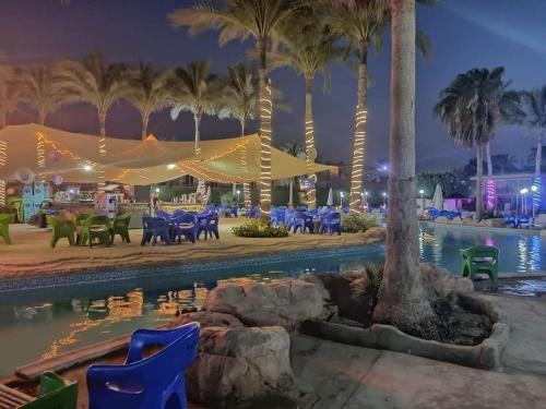 una piscina en un complejo por la noche con palmeras en Chalet at Lasirena Mini Egypt Resort Ein Elsokhna Families Only, en Ain Sokhna