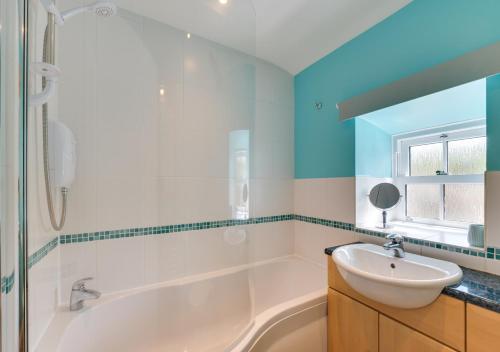 een badkamer met een wit bad en een wastafel bij The Cottage in Thwaite