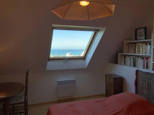 een slaapkamer met een raam met uitzicht op de oceaan bij Maison face l’Ocean in Plozévet