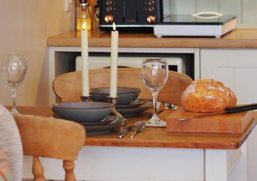 a table with two candles and a table with bread and wine glasses at The Bothy in Carlton