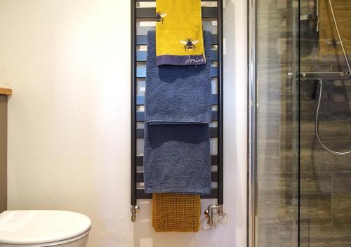 uma casa de banho com toalhas azuis e amarelas e um chuveiro em The Bothy em Carlton