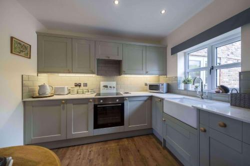 a kitchen with white cabinets and a sink at The Hoglets 2 in Goostrey