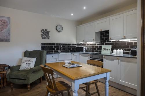 a kitchen with white cabinets and a table and chairs at The Hoglets 3 in Goostrey