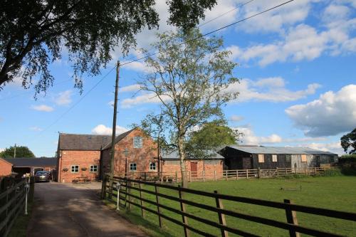 an old brick building with a fence next to a field at The Hoglets 3 in Goostrey