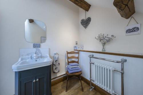 a bathroom with a sink and a mirror and a chair at The Hoglets 3 in Goostrey