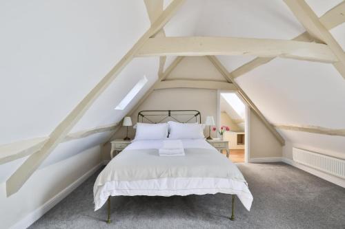 ein Schlafzimmer mit einem weißen Bett im Dachgeschoss in der Unterkunft Coombers Mead Cottage in Tetbury