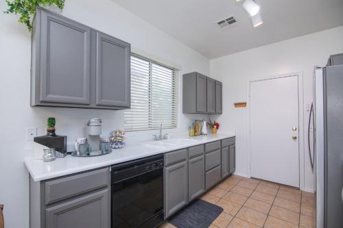 a kitchen with gray cabinets and a sink and a refrigerator at Stylish Home Phoenix - Low Rates NOW! in Phoenix
