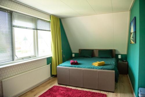 Un dormitorio con una cama con paredes verdes y una ventana en Heerlijk genieten. en Hoogersmilde