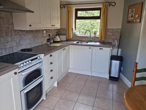 a kitchen with white cabinets and a sink at Osprey Meadow Holiday Cottages in Bedale