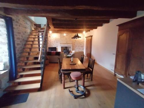 a dining room with a table and a staircase at Le Temps Serein in Vabre-Tizac