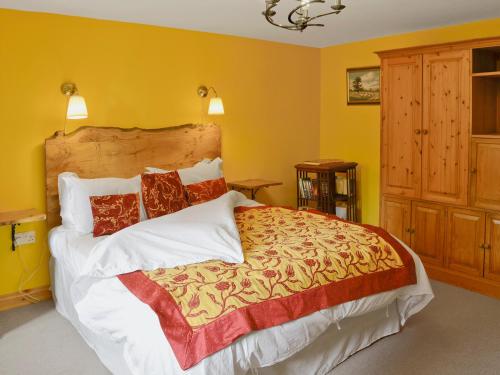 een slaapkamer met een groot bed met gele muren bij Tucked Away in Linkinhorne