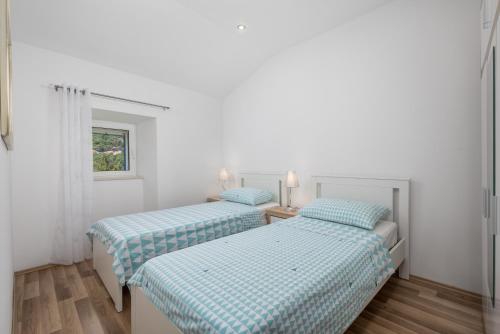 two beds in a room with white walls at House Bajota with terrace and sea view in Beli