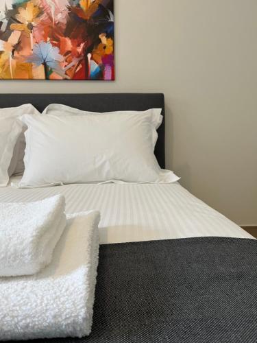 a bed with white pillows and a painting on the wall at Aellō luxury apartments in Markopoulo
