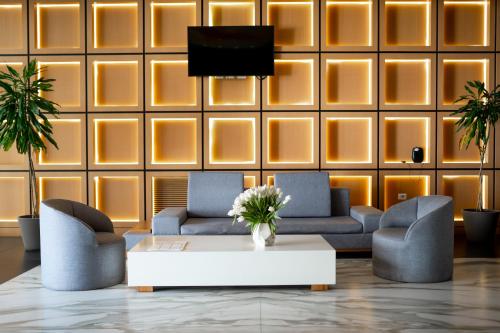 a lobby with two couches and a tv on a wall at Royal G Max in Golem