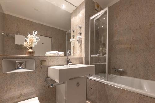 uma casa de banho com um lavatório, um espelho e uma banheira em Dreams Beckum em Beckum