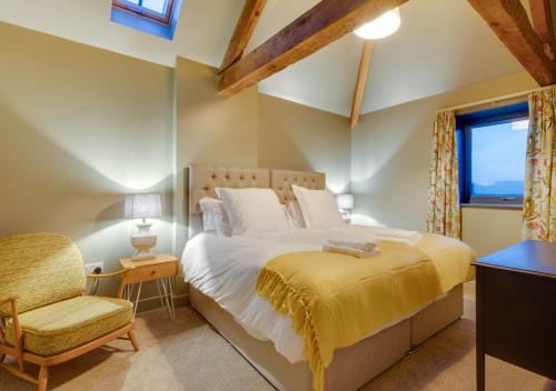 a bedroom with a bed and a chair and a window at The Barn at The Foldyard in Holme upon Spalding Moor