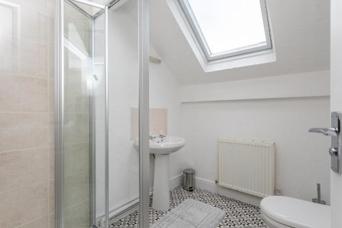 a white bathroom with a sink and a shower at Victoria Parade in Rossendale