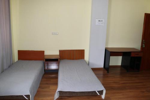 two beds in a room with a desk and a table at Tvishi Guest House in Tsʼageri
