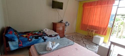 Habitación con cama, mesa y TV. en koryares haushostel en Puerto Maldonado