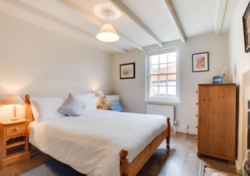 een slaapkamer met een groot wit bed en een raam bij Storm Cottage in Robin Hood's Bay