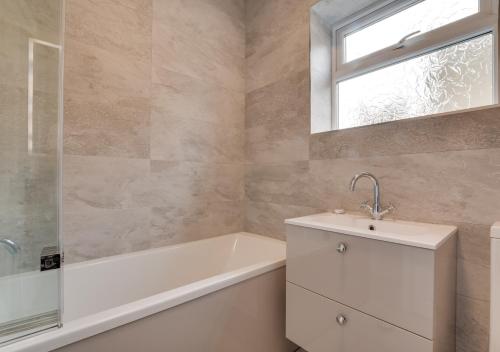 La salle de bains est pourvue d'une baignoire, d'un lavabo et d'une fenêtre. dans l'établissement Starlight Cottage, à Whitby