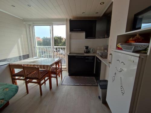 une cuisine avec une table, des chaises et un réfrigérateur dans l'établissement LE COLISEE Joli studio cabine Mt St Martin proche port Cap d'Agde, au Cap d'Agde