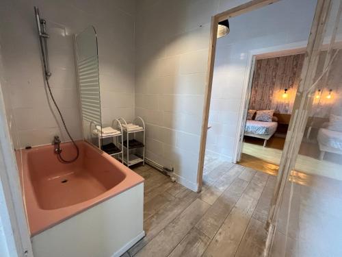 a bathroom with a pink tub and a bedroom at Hotel l'Entracte in Saint-Paul-du-Bois