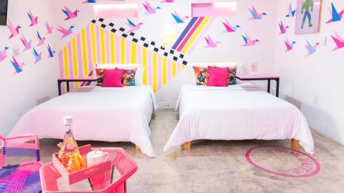 two beds in a room with colorful flags on the wall at Hotel Suculenta Boutique in San Cristóbal de Las Casas