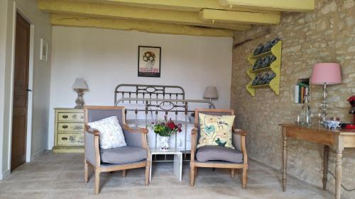 une pièce avec deux chaises, une table et un lit dans l'établissement Les Fleurs d'Ans, à Sainte-Eulalie-dʼAns
