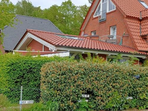 una casa de ladrillo rojo con un seto delante de ella en Moderne Ferienwohnung mit Kamin u Garten im EG 100qm Nähe Weser und Golfplatz, en Achim