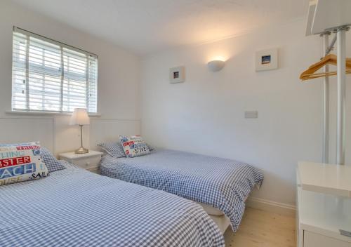 Habitación pequeña con 2 camas y paredes blancas. en Cliff Top Cottage en Porthleven
