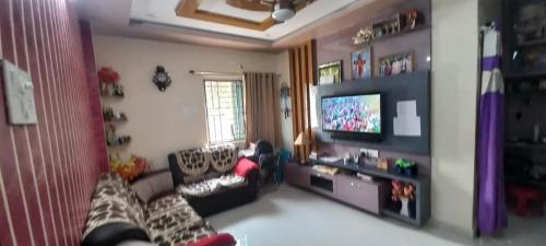 een woonkamer met een bank en een flatscreen-tv bij Assan Place in Bhubaneshwar