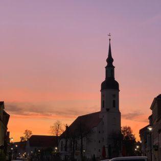a church steeple with a cross on the top at sunset at SPREE. Hotel am Hafen in Lübbenau