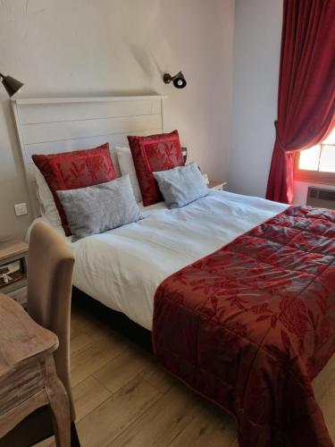 a bedroom with a large bed with red pillows at Logis Hôtel-Restaurant Le Relais in Hauterives