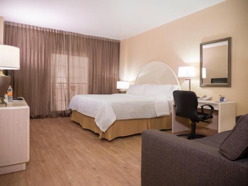 a hotel room with a bed and a chair at Holiday Inn Express Torreon, an IHG Hotel in Torreón