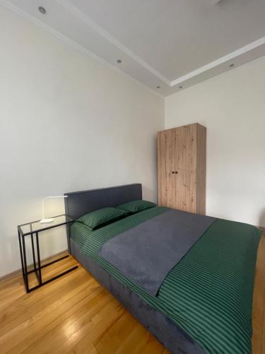 een slaapkamer met een groen bed en een houten vloer bij Apartment with the view of the Opera House in Lviv