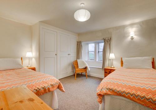 sypialnia z 2 łóżkami, krzesłem i oknem w obiekcie South View Cottage w mieście Horton in Ribblesdale
