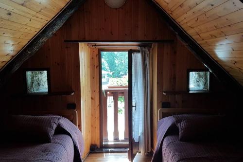 a attic room with two beds and a large window at La Cà Rustica - casa vacanze in Bognanco