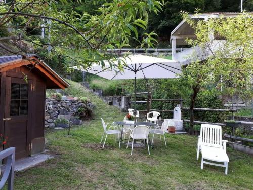 una mesa y sillas en un patio con sombrilla en La Cà Rustica - casa vacanze, en Bognanco